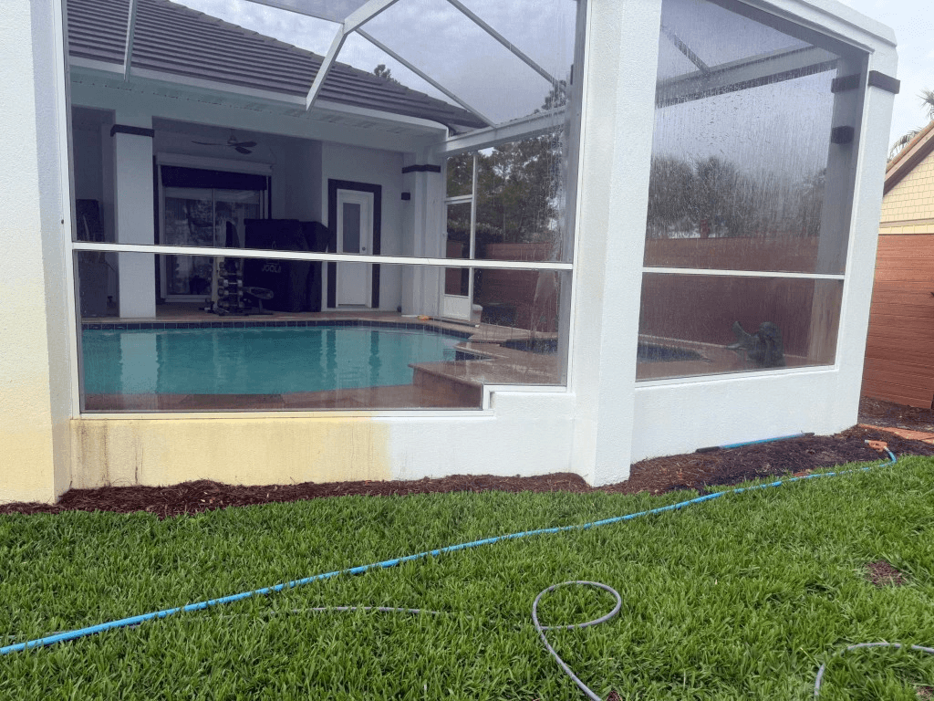 Before and after pressure washing on a white pool enclosure wall