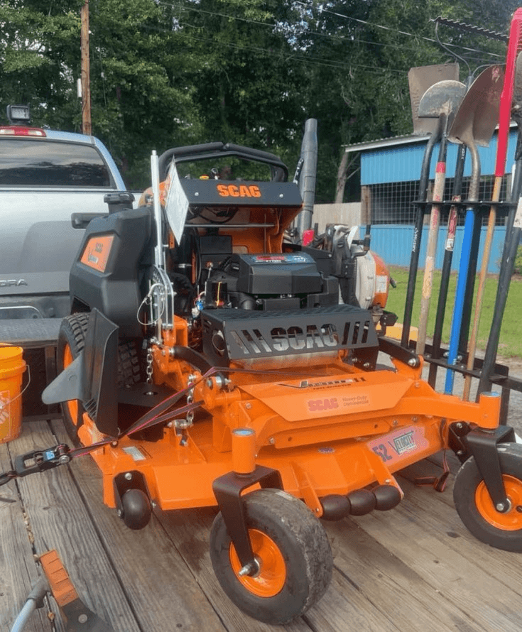 Scag stand-on mower and landscaping equipment loaded on a trailer